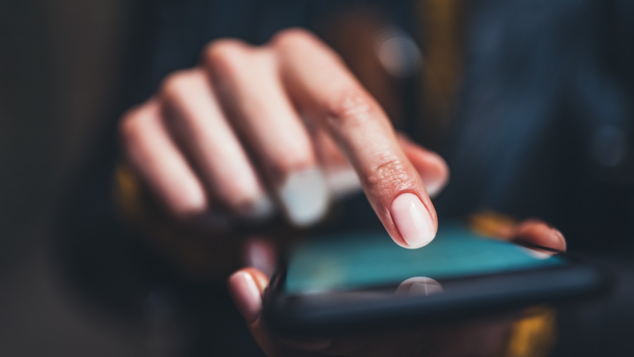 Photo closeup of a finger tapping a smartphone screen. We offer adhesive tapes for electonics gasketing applications.